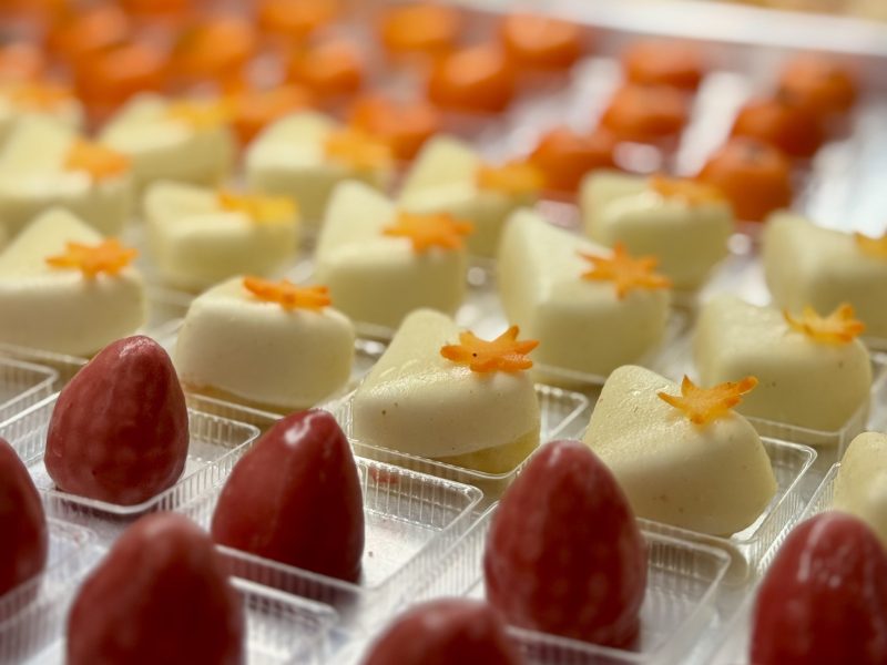 Assorted desserts with red and white toppings in clear trays, arranged in rows.