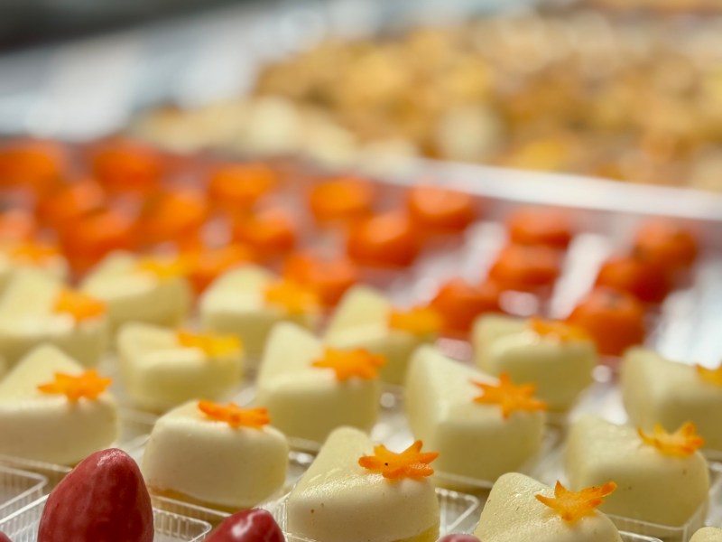 Assorted desserts with red and white toppings in clear trays, arranged in rows.