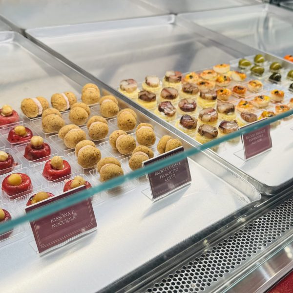 Display case with assorted gourmet pastries and labels in a bakery.