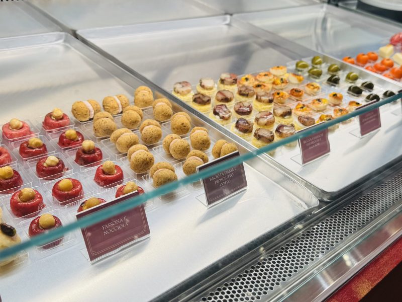 Display case with assorted gourmet pastries and labels in a bakery.