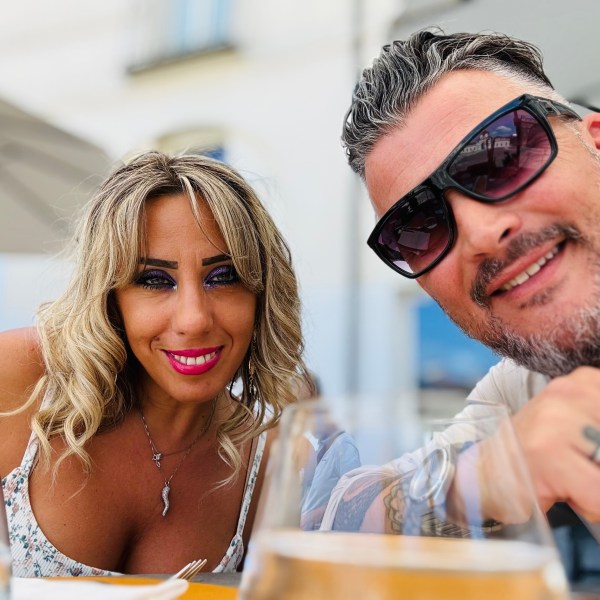 Smiling couple at an outdoor restaurant with drinks on the table.