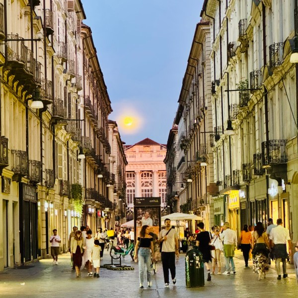 Street scene with people walking and a building under a full moon.