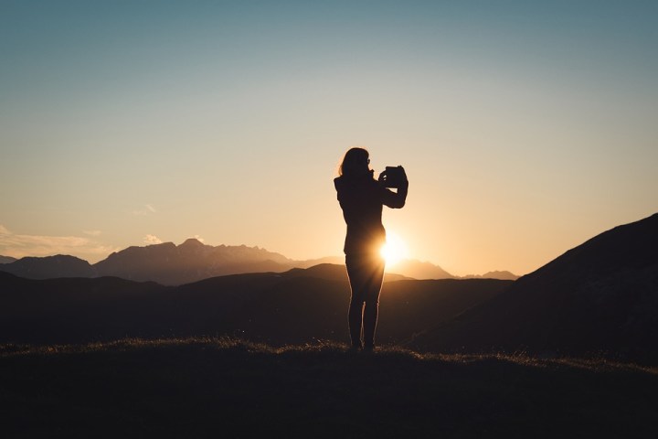 a person standing on a hill with a sunset in the background
