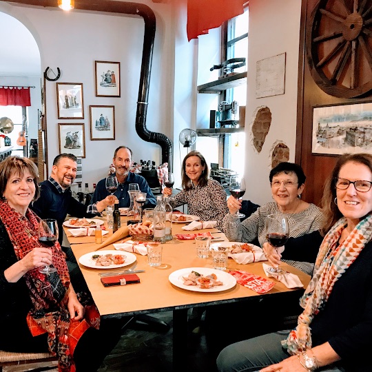 People sitting around the table, eating and drinking wine