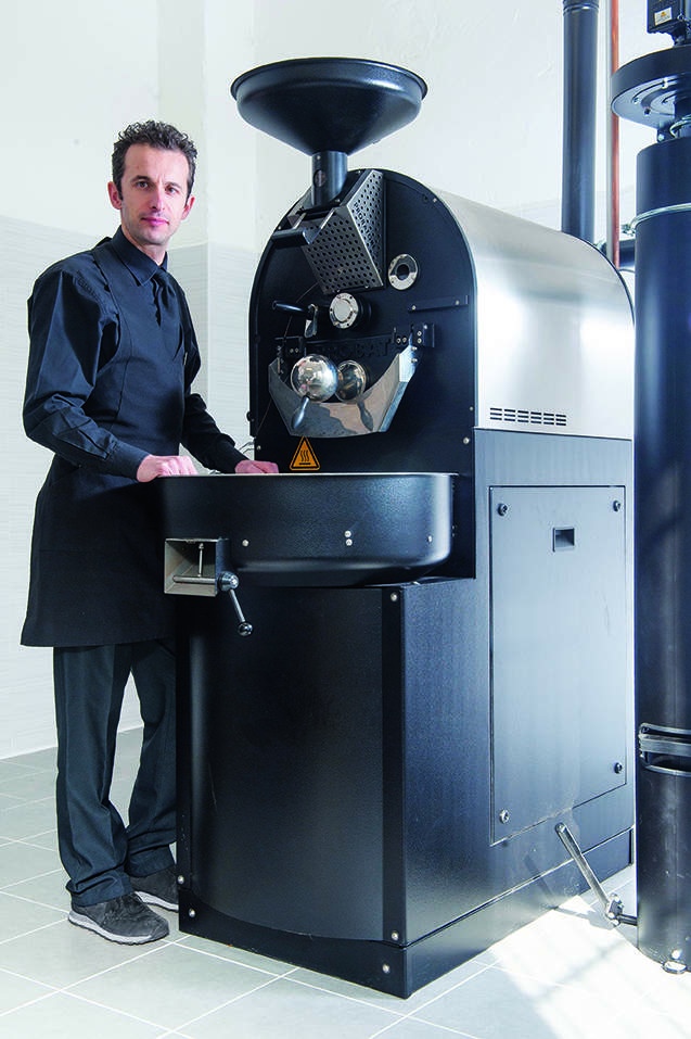 a man standing in front of a coffee roaster