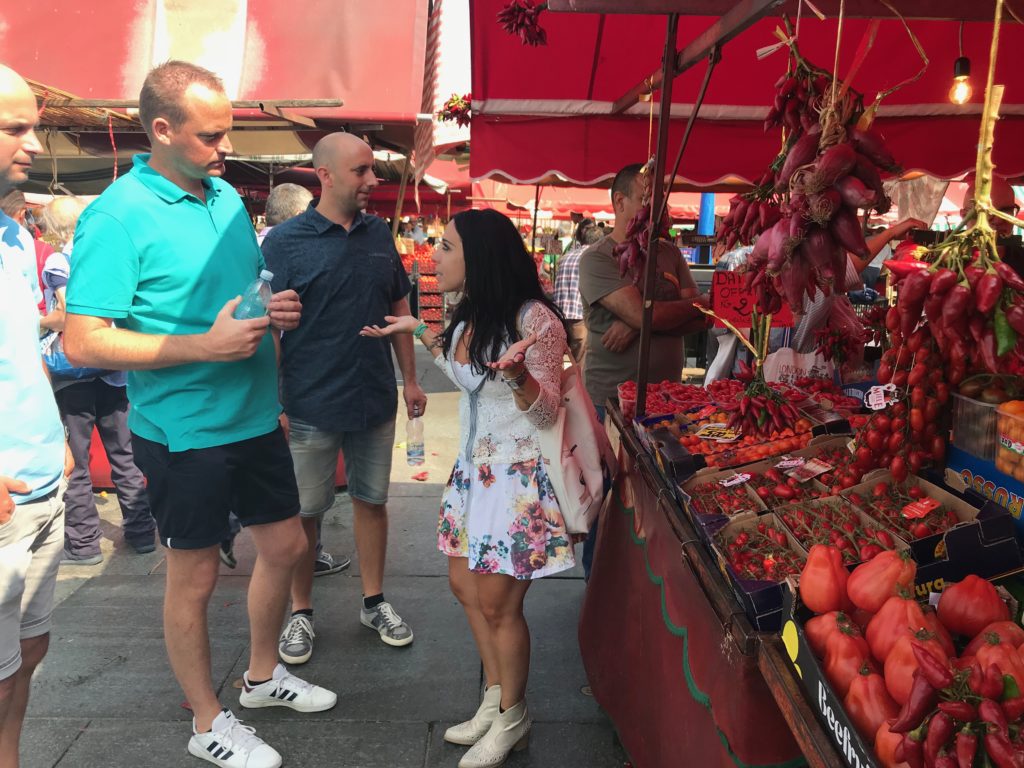 a group of people standing in front of a fruit stand