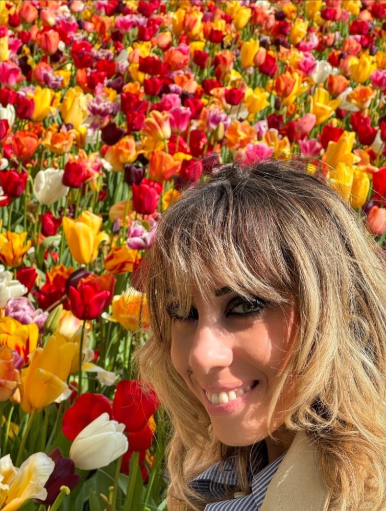 a woman standing in front of a flower