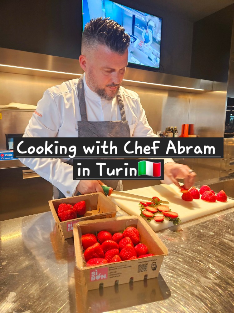 a chef sitting at a table in front of a fruit stand