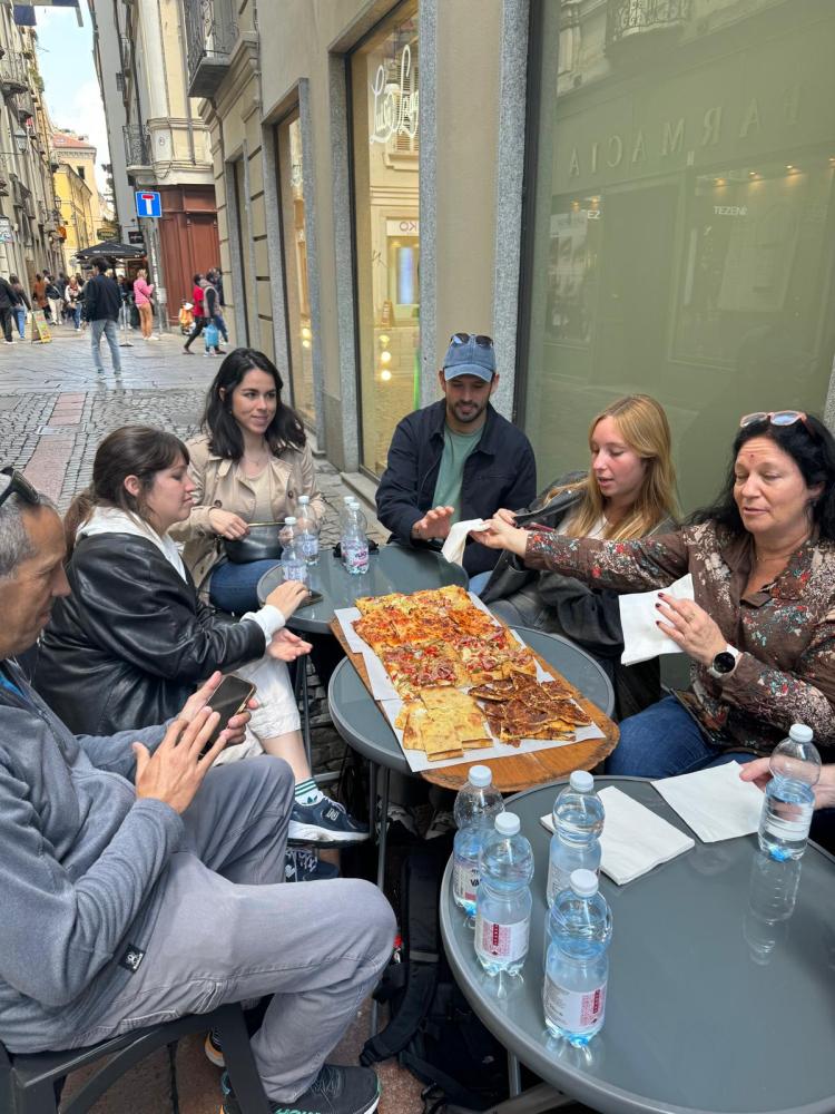 a group of people sitting at a table eating pizza