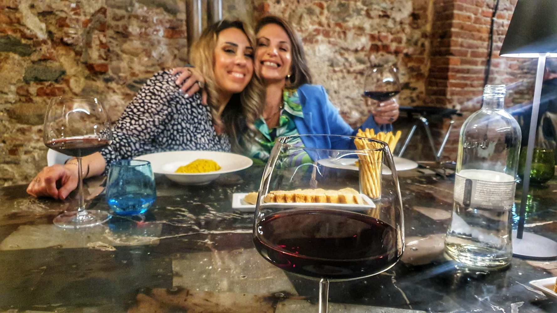 a woman sitting at a table with a glass of wine