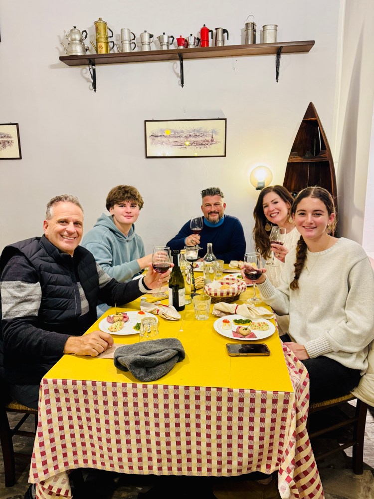 A group of people sitting around the table with wine