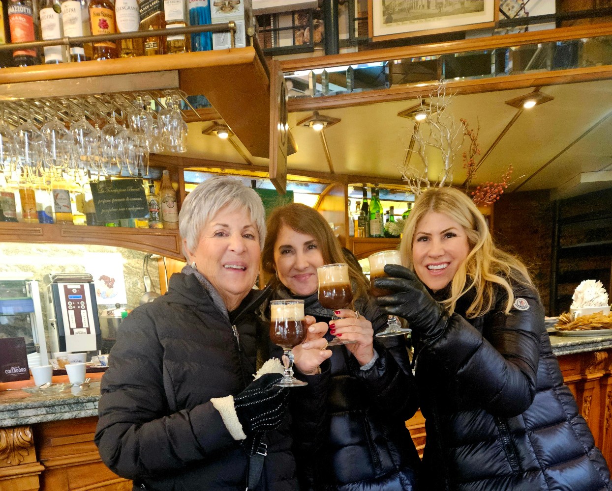 Women standing and smiling holding a cup of chocolate 