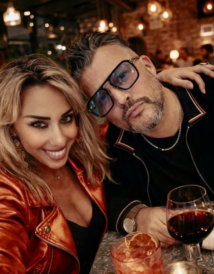 Two people smiling at a restaurant table with cocktails and candlelight.