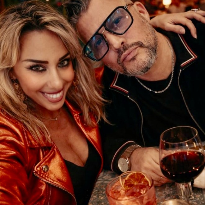 Two people smiling at a restaurant table with cocktails and candlelight.