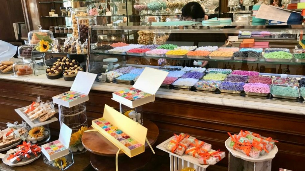 Colorful candy display in a sweet shop with various trays and gift boxes.