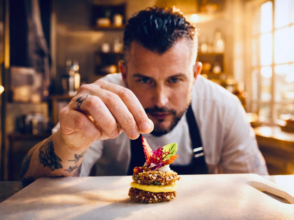 Chef garnishing a gourmet dish with precision in a warmly lit kitchen.