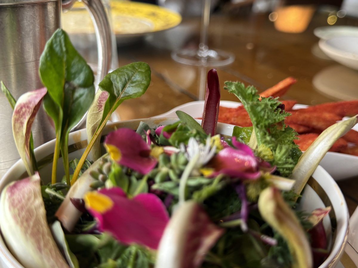 Close-up of a colorful salad with edible flowers and leafy greens on a restaurant table.
