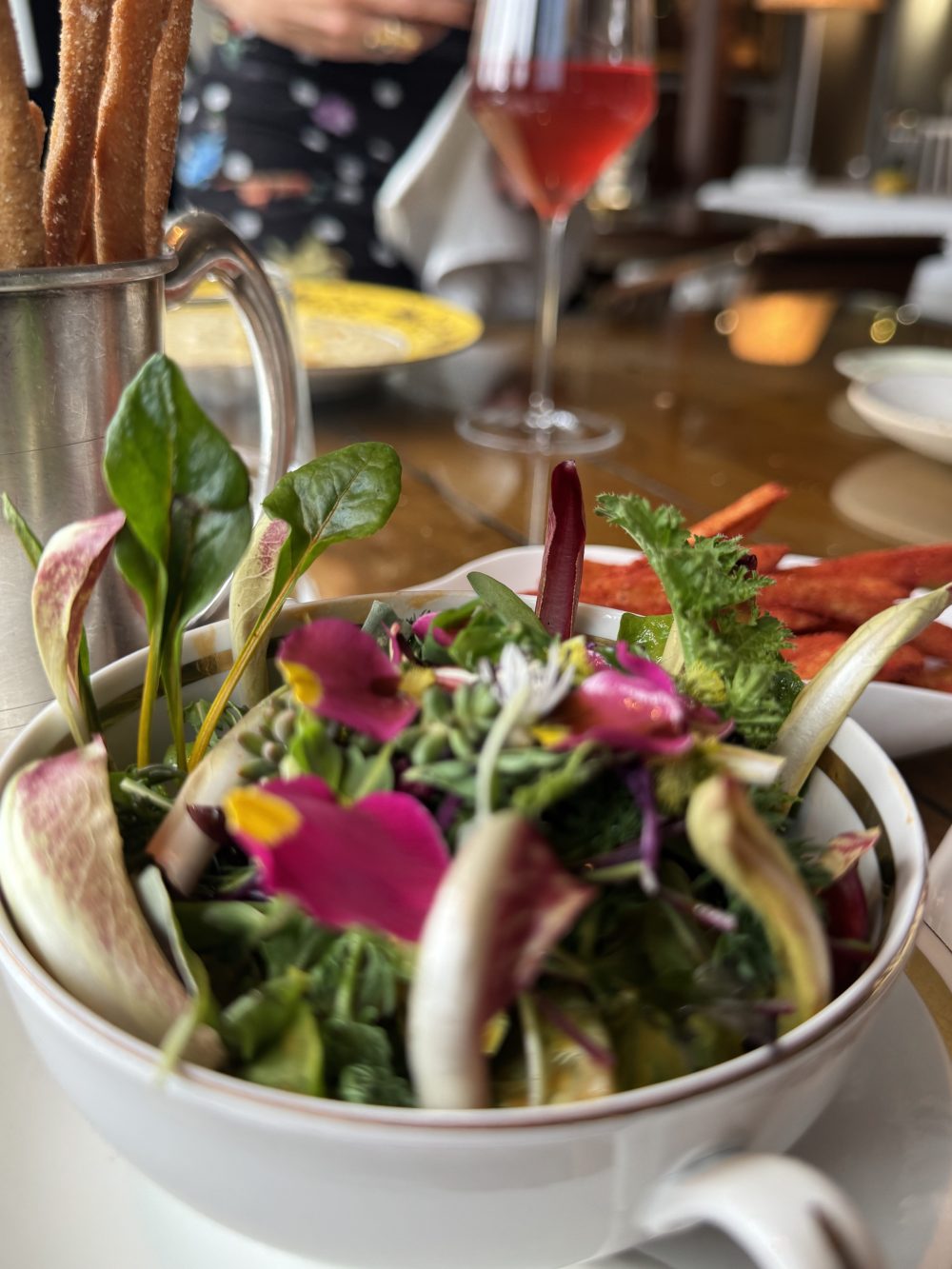 Close-up of a colorful salad with edible flowers and leafy greens on a restaurant table.