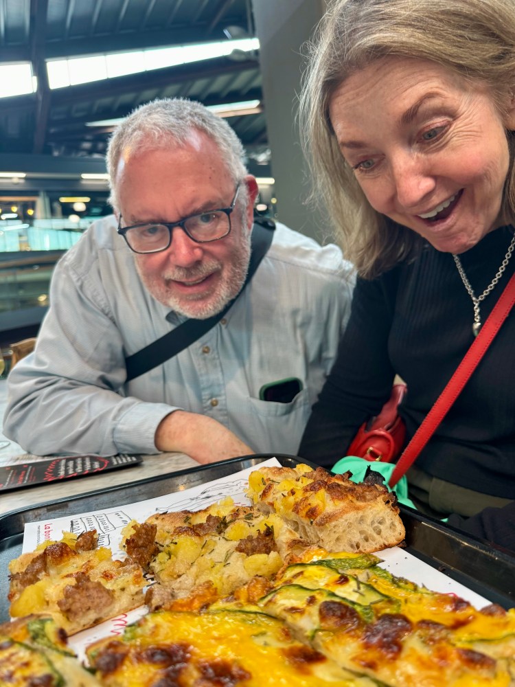 Two people excitedly look at a tray of food with assorted dishes.