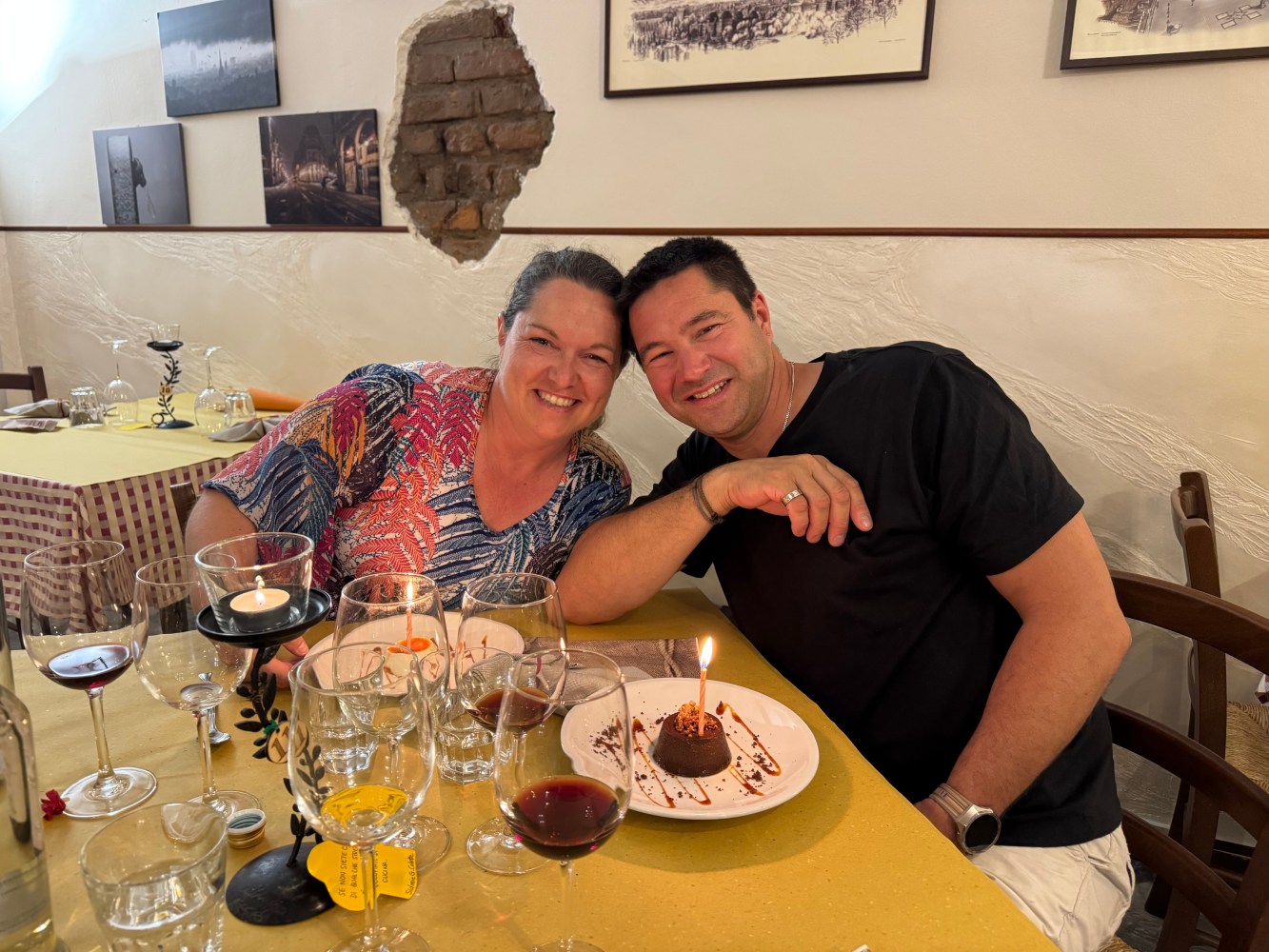 Smiling couple at restaurant table with dessert and candle.