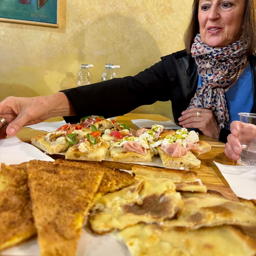Woman at a table with various slices of pizza and focaccia.
