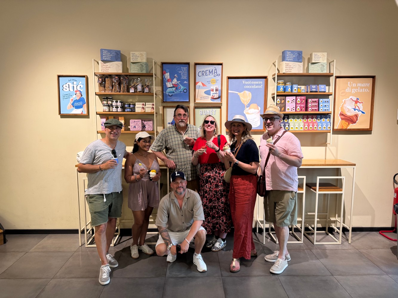 Group posing with ice creams in front of a dessert-themed wall display.