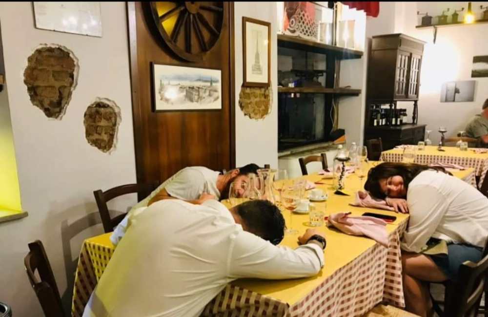 Three people asleep at a table in a rustic restaurant setting.