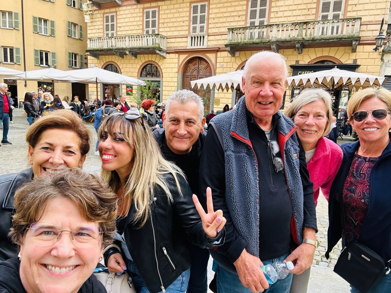 Group of smiling people pose outside in front of historic buildings.